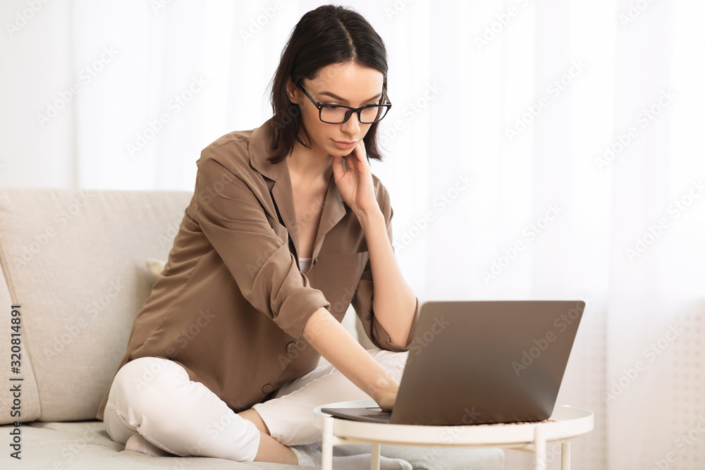 Young woman using laptop sitting on the couch Young woman using laptop sitting on the couch