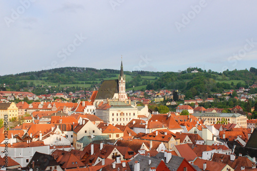 View of the village of Cesky Krumlov and green hill from the Castle, with St. Vitus Church at the background, in Czech Republic