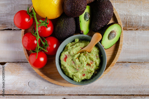 Tasty and healthy mexican snack: avocado guacamole. Homemade, served on a wooden rustic table with raw ingredients. Delicious and low calorie meal. Copy space for text, flat lay