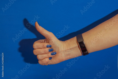 female hand showing thumb up on blue background