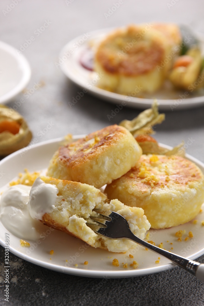 Breakfast. Cheesecakes with sour cream and jam on a light background. Background image, copy space Breakfast. Cheesecakes with sour cream and jam on a light background. Background image, copy space