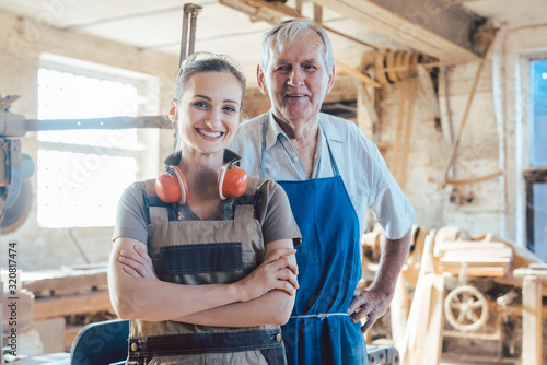 Tableau sur toile Senior master carpenter with his granddaughter in the wood workshop
