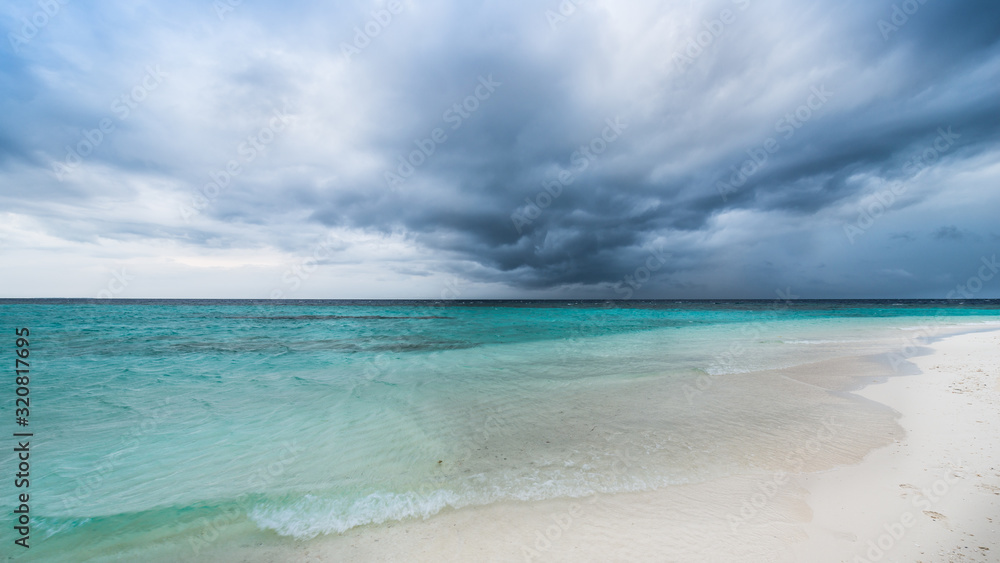 Storm over the ocean. White sand on the beach of a tropical island.