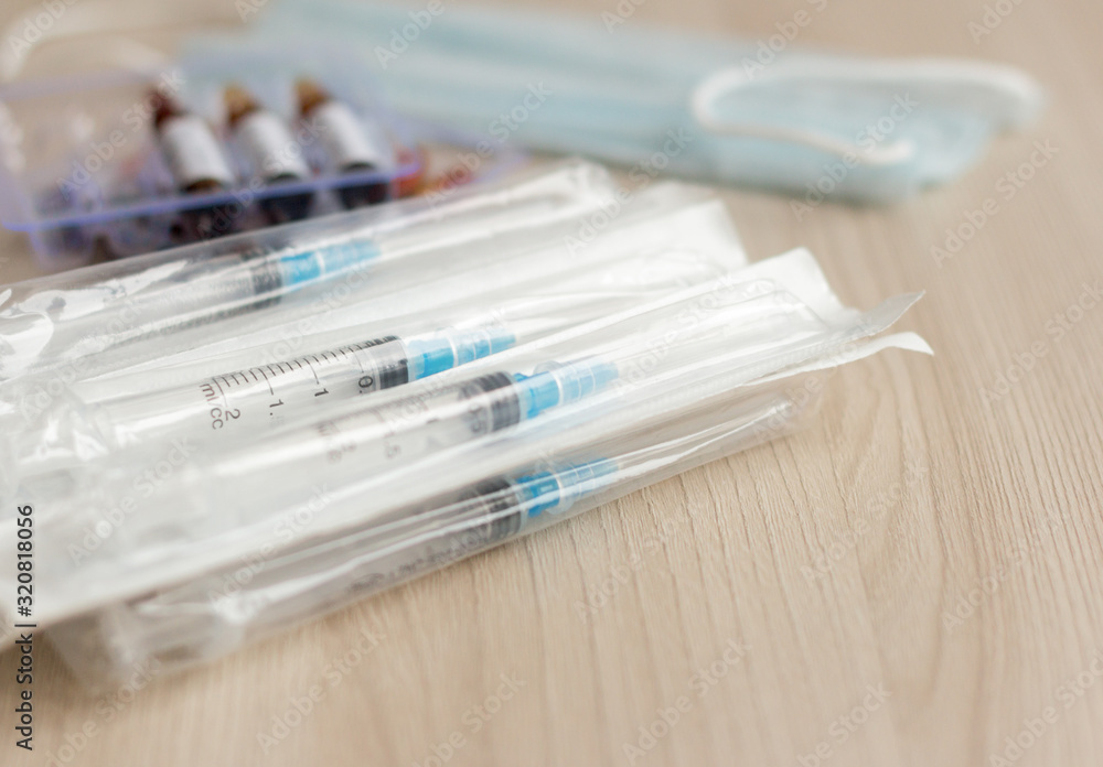 Syringes in the package, ampoules with medication and a mask on a light background.The concept of prevention of viral diseases. Syringes in the package, ampoules with medication and a mask on a light background.The concept of prevention of viral diseases.