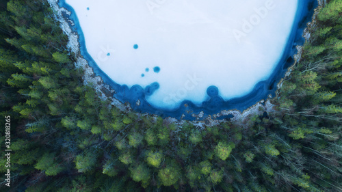 Aerial view of a frozen lake in the middle of a Scandinavian forest.