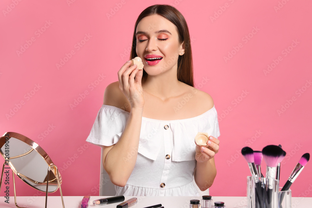 Beauty blogger applying lip balm on pink background