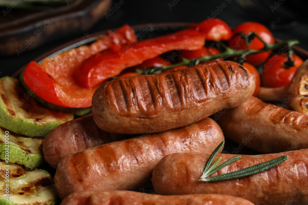 Tasty fresh grilled sausages with vegetables on table, closeup Tasty fresh grilled sausages with vegetables on table, closeup