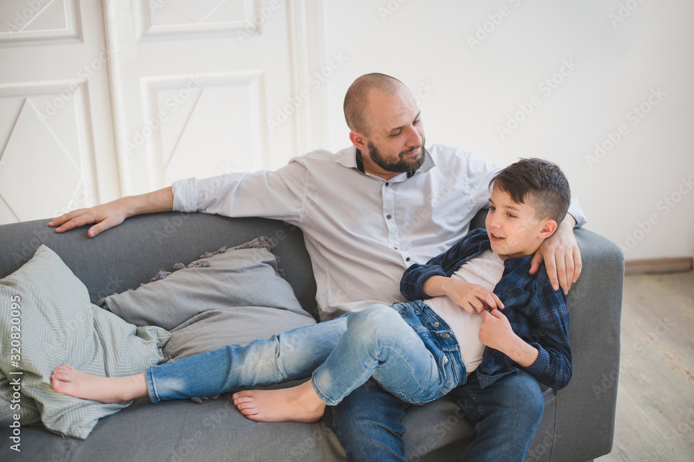 Daddy with son relaxing on sofa.
