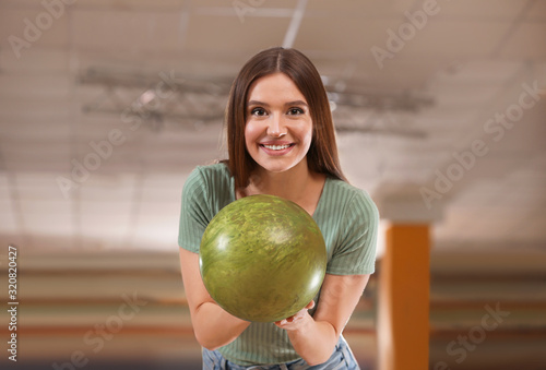 Young woman with ball in bowling club