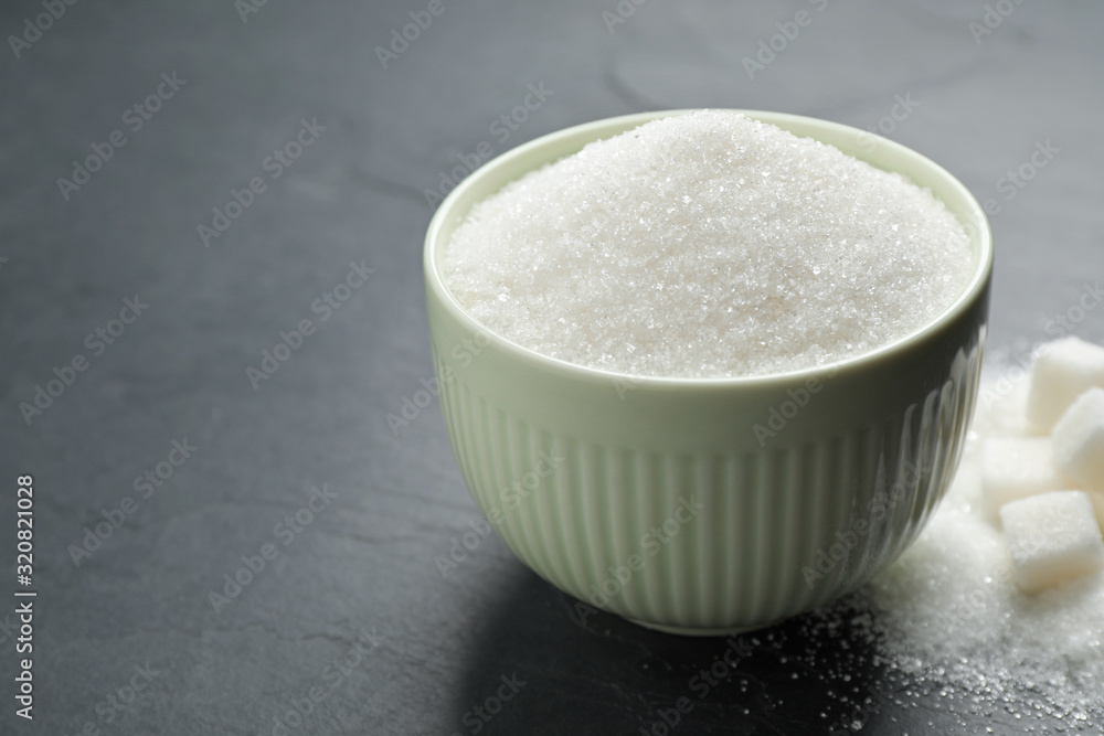 Granulated sugar in bowl on dark table Granulated sugar in bowl on dark table