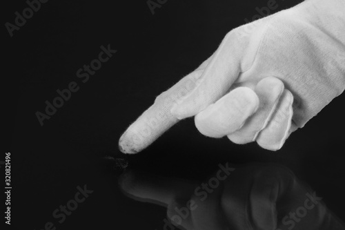 Person in white glove checking cleanliness of black background, closeup
