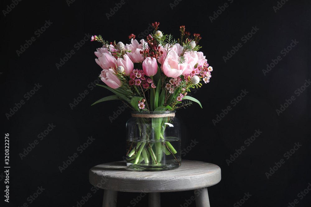 Fototapeta premium Beautiful bouquet with spring pink tulips on wooden table against black background