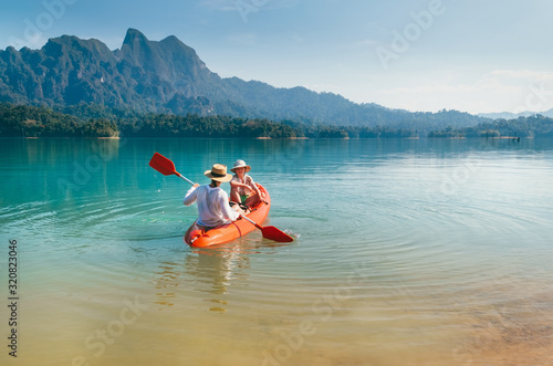 Mother and son floating on kayak together on Cheow Lan lake in Thailand. Traveling with kids concept image.