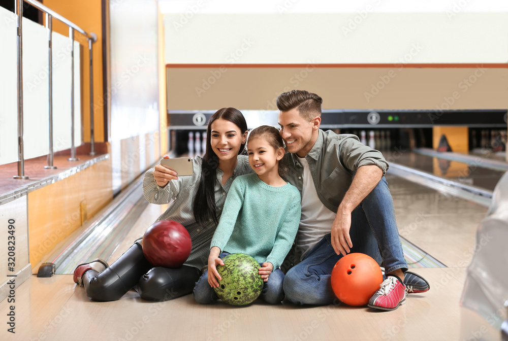 Fototapeta premium Happy family taking selfie in bowling club