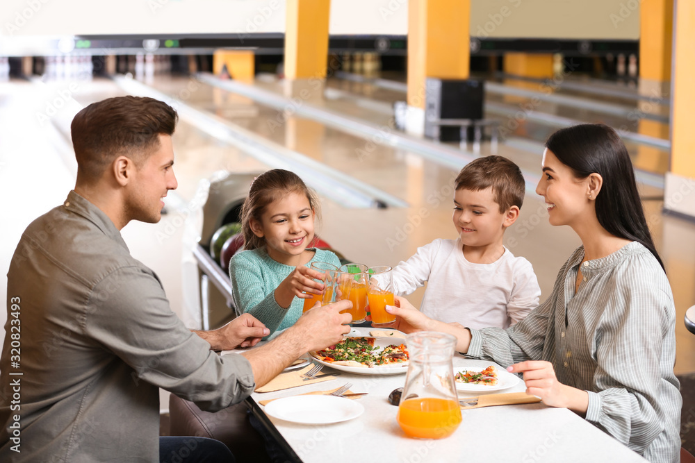 Happy family with pizza and drinks in bowling club Happy family with pizza and drinks in bowling club