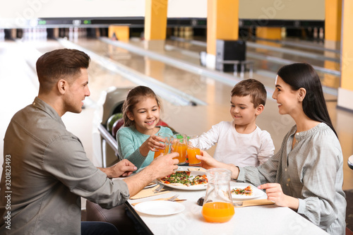 Happy family with pizza and drinks in bowling club