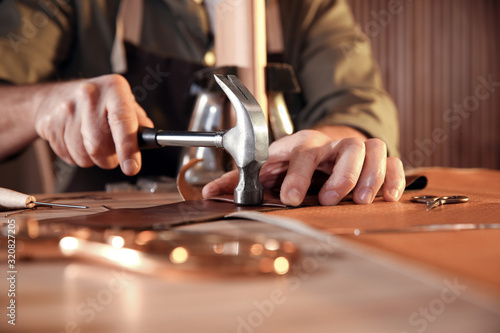 Man working with piece of leather at table, closeup