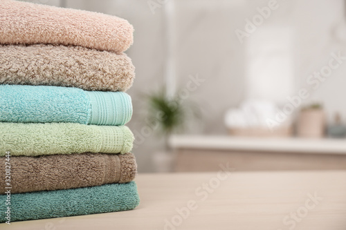 Stack of fresh towels on wooden table in bathroom, closeup. Space for text