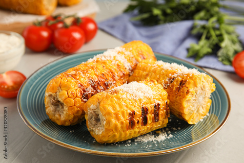Delicious grilled corn cobs on light grey table