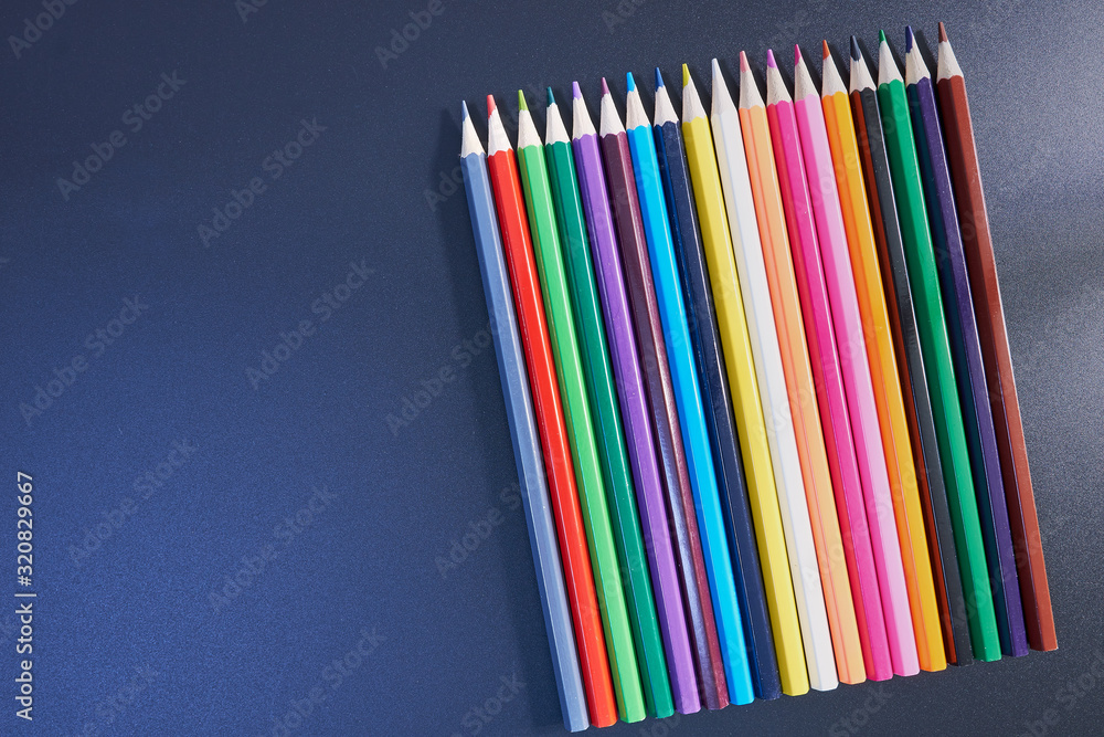 A rainbow of colored pencils, on a gray, black, dark background. copy space A rainbow of colored pencils, on a gray, black, dark background. copy space