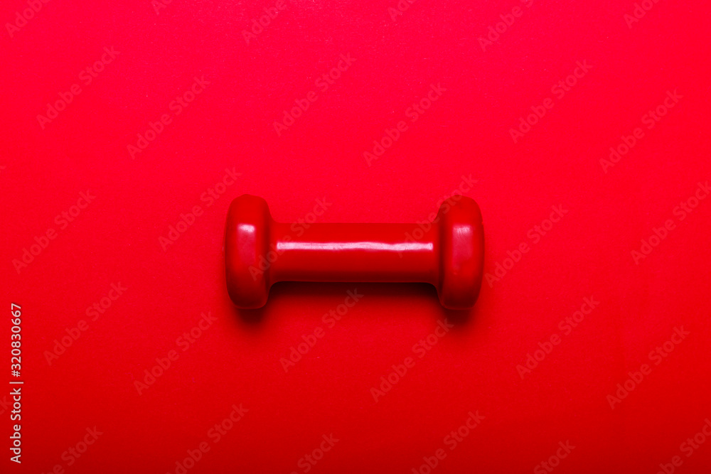 Red dumbbell for fitness isolated on dark red background. Red dumbbell for fitness isolated on dark red background.