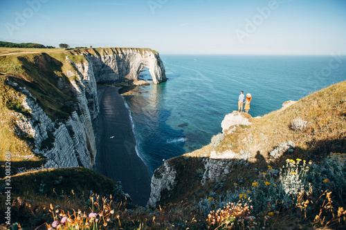 Couple looking at Etretat cliffs along the ocean shore in France photo