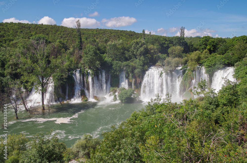 Beautiful view of Kravica waterfalls after heavy rains. Large tufa cascade on Trebizat River, in karstic heartland of Herzegovina. Lush surrounding and rich riparian ecosystem. Bosnia and Herzegovina