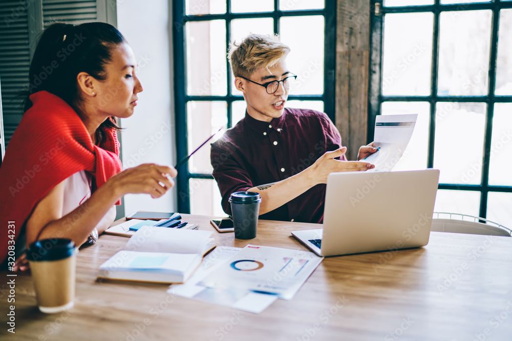 Fototapeta premium Young colleagues checking diagram in office