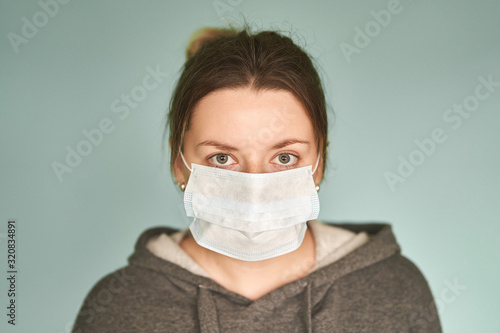 Girl in a medical mask on a green background. Coronavirus. Prevention of viral diseases