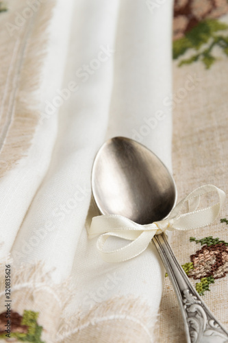 Vintage russian silverspoon with silk ribbon on linen napkin. Old fashion heroloom silverware photo