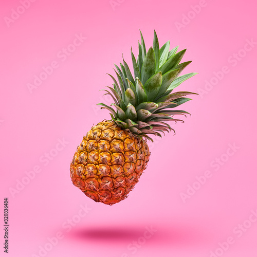 Flying in air pineapple tropical fruit on pink. Healthy vitamin pineapple, vegan dieting food. Organic whole sweet fresh fruits. Levitation, falling fly pineapple creative concept