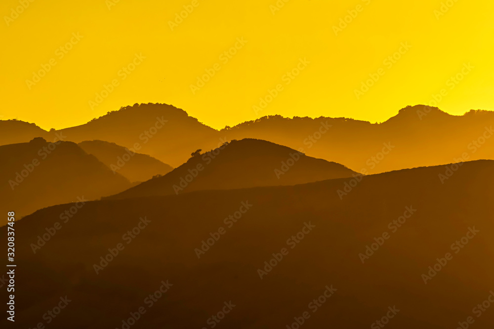 Silhouetted Hills at Sunset with Yellow Glow Silhouetted Hills at Sunset with Yellow Glow