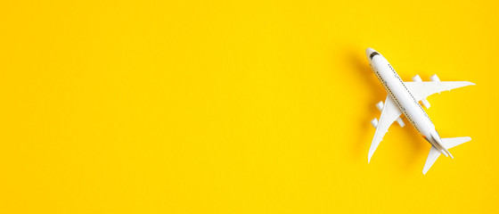 Miniature toy airplane on yellow background with copy space. Summer holiday air travel by plane concept. Travel agency banner design template, banner or header mockup