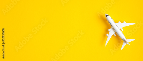 Miniature toy airplane on yellow background with copy space. Summer holiday air travel by plane concept. Travel agency banner design template, banner or header mockup photo