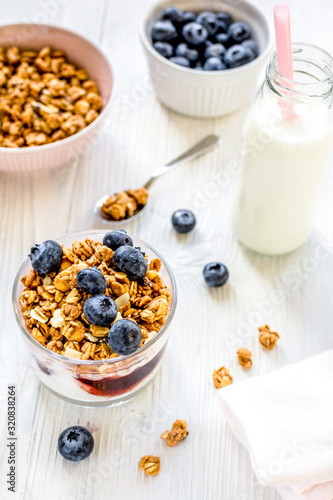 Fitness breakfast with granola, milk and berries on white background