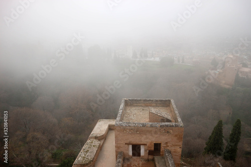 Amazing view to the tower of Alhambra citadel alcazaba in the winter morning fog, Granada, Spain
