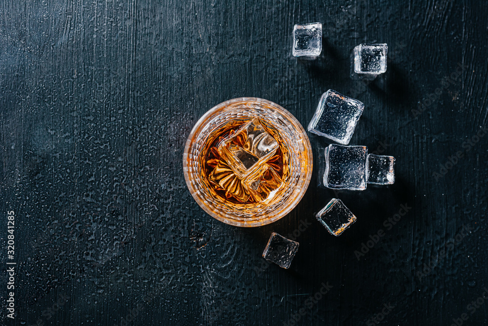 glass of whiskey with ice on a wooden table surrounded by smoke glass of whiskey with ice on a wooden table surrounded by smoke