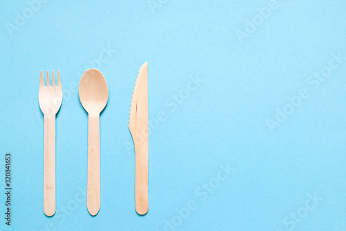 Wooden fork  spoon and knife on a blue background  top view. Disposable eco dishes