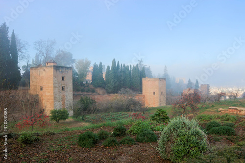 Winter garden and Alhambra towers and wall in the morning haze, Granada, Spain
