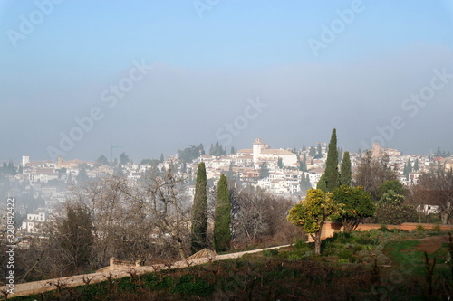 Panoramic view to Granada city in the morning fog from Generalife gardens