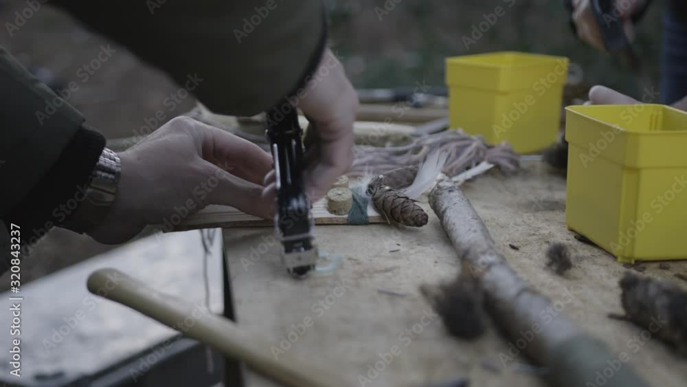 A man is crafting a puppet out of things he found in nature A man is crafting a puppet out of things he found in nature