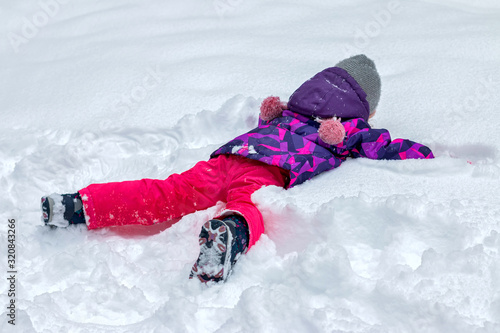 The child is lying in the snow
