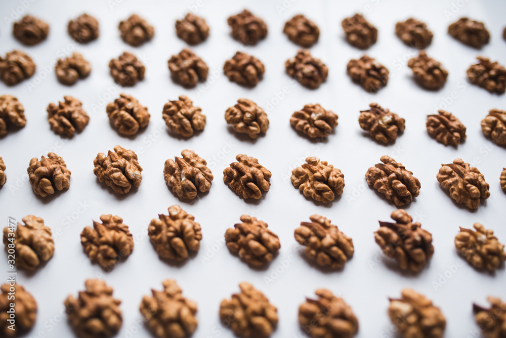 Pattern of walnuts on a white background. Top view on a nuts pattern. Pattern of walnuts on a white background. Top view on a nuts pattern.