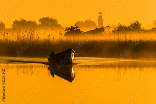 Fisherman is returning to the harbour in Sulina in orange sunraise. Danube delta, Romania