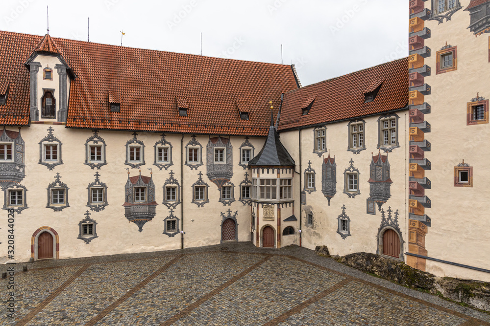 View of a corner of the backyard of the Hohes Scloss castle in Fussen on a cloudy winter day, with beautiful painting on facade, Allgaeu, Bavaria, Germany