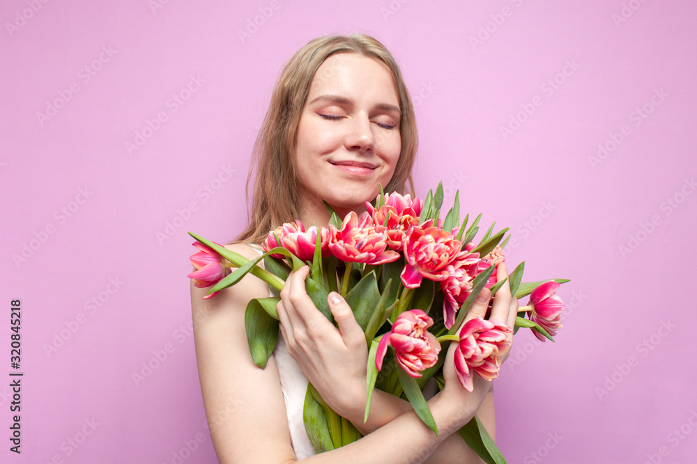 girl holds and sniffs a bouquet of flowers on a pink background, a beautiful woman with tulips girl holds and sniffs a bouquet of flowers on a pink background, a beautiful woman with tulips
