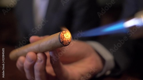 Business man lights cigar with lighter