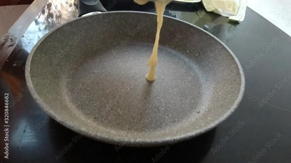 Pouring some dough on a hot frying pan to cook a pancake. Pouring some dough on a hot frying pan to cook a pancake.