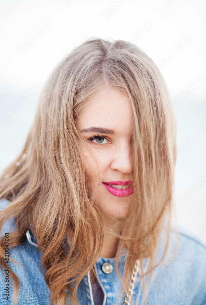 Young beautiful woman in denim jacket and knit hat against the sea Young beautiful woman in denim jacket and knit hat against the sea