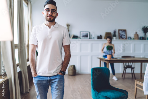 Confident man standing with hands in pockets at home